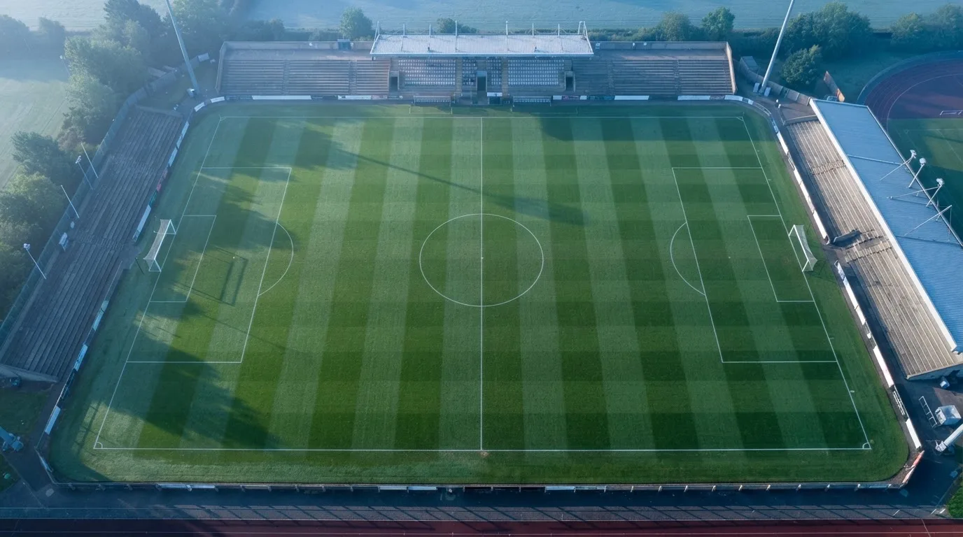 Ein Fussballplatz von oben gesehen, die Linien bilden ein helles Muster auf dem Rasen, Drohnenperspektive in der Morgendämmerung.