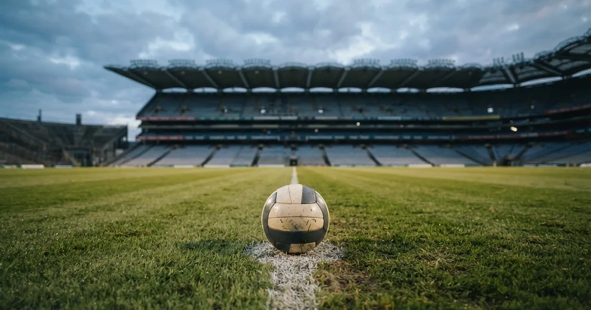 Ein Fussball liegt auf dem Anstosspunkt eines frisch gemähten Rasens, dahinter eine grosse Tribüne unter bewölktem Himmel